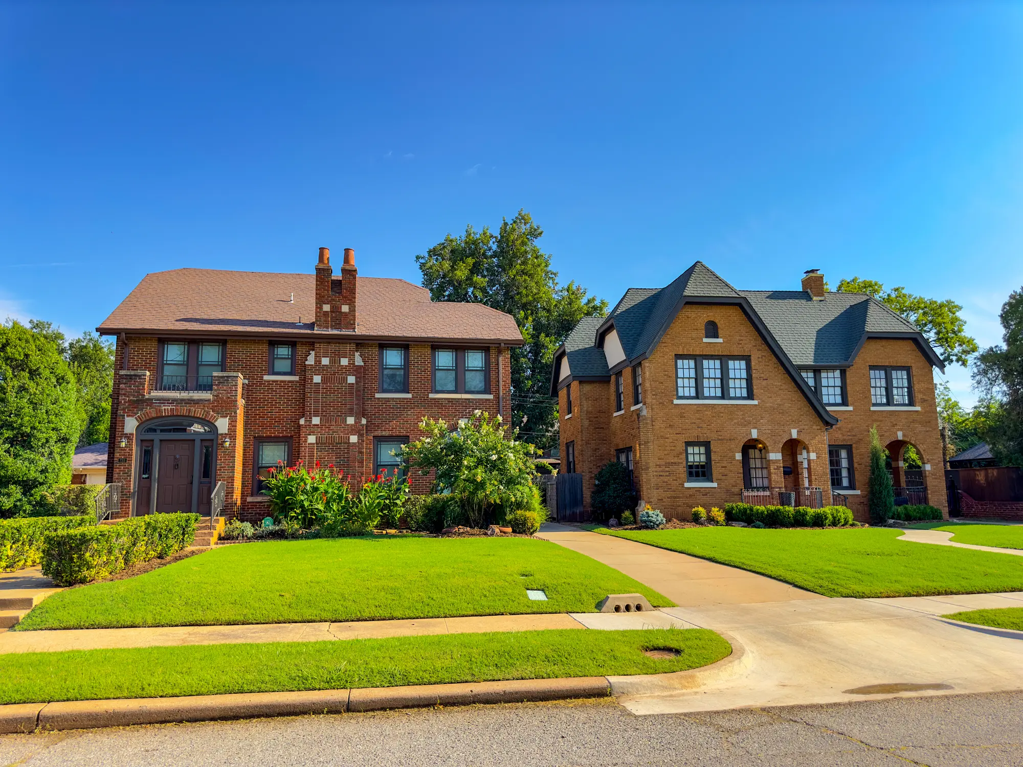 Two brick suburban houses with manicured lawns