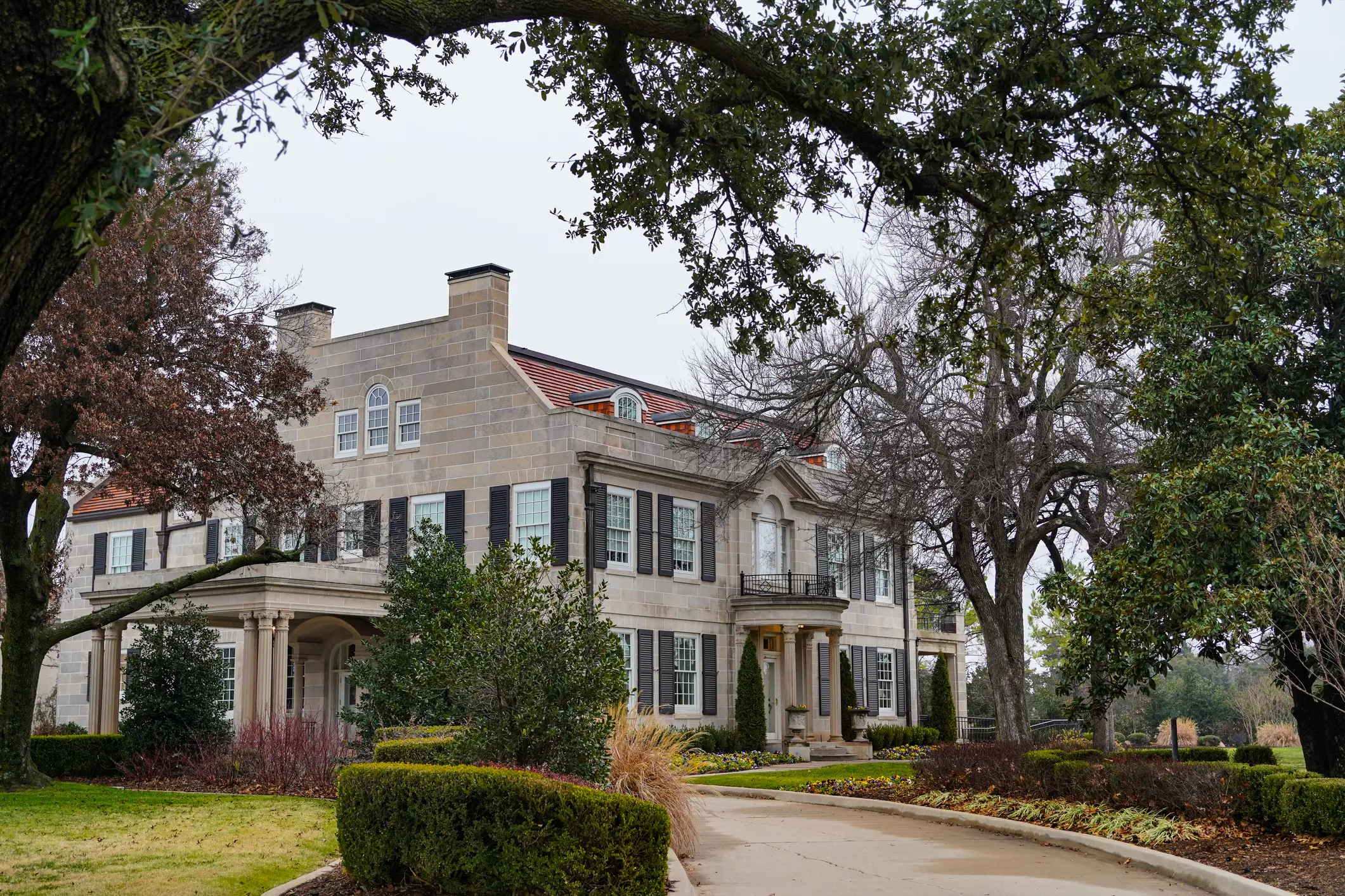Large stone mansion surrounded by mature trees