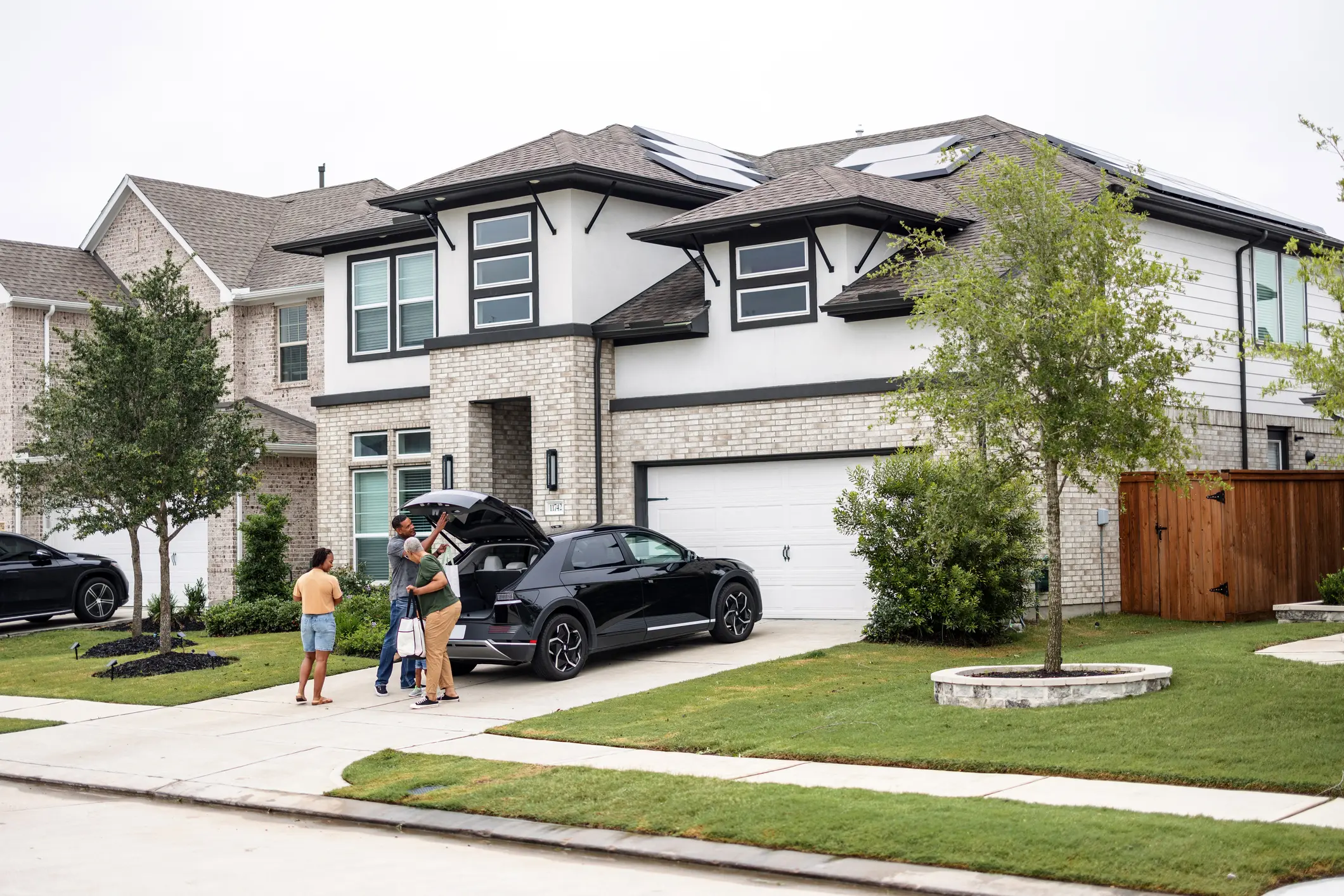 Family loading car in driveway of modern house