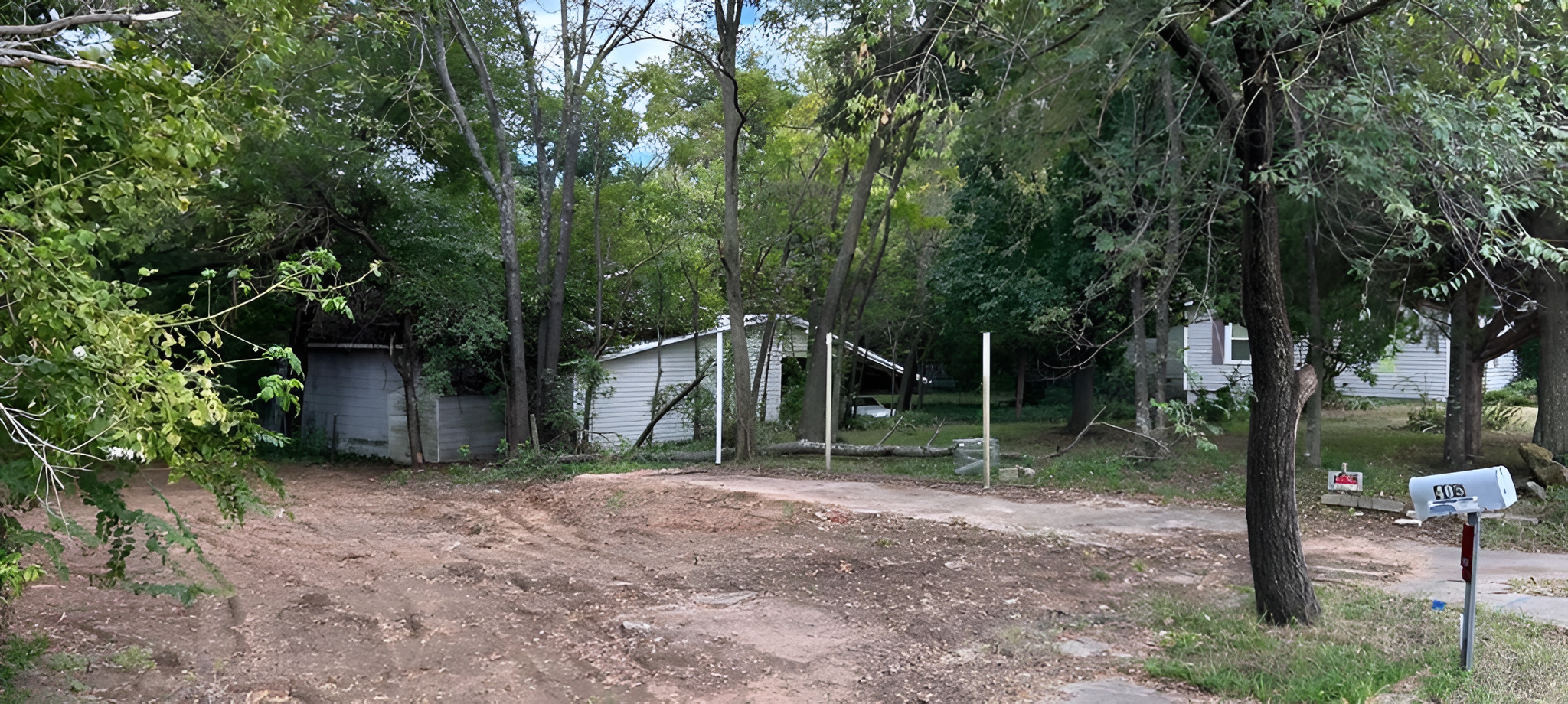 Cleared dirt lot with trees and houses